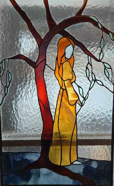 A stained glass of a woman and a tree