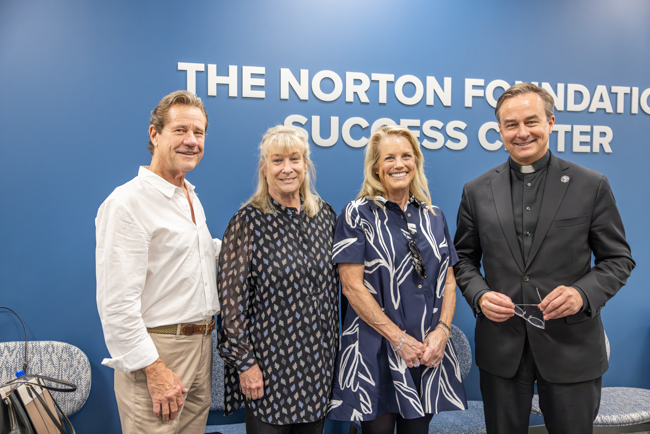 Fr. Hendrickson, right, with members of the Norton family in The Norton Foundation Success Center.