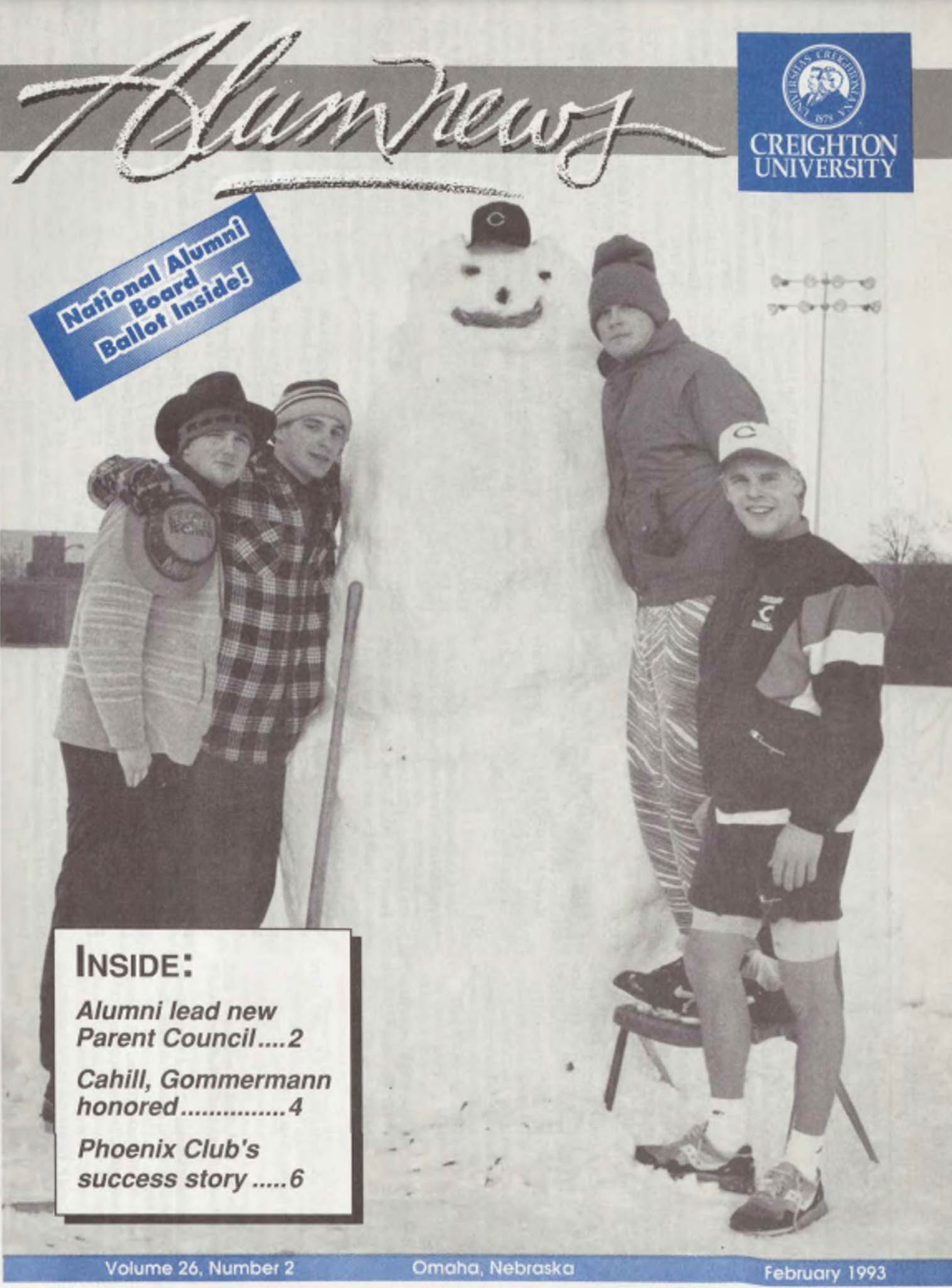 One student stands on a chair and three others gather around a large snowman