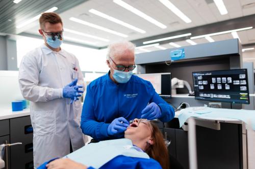 Professor and student dentist work on patient