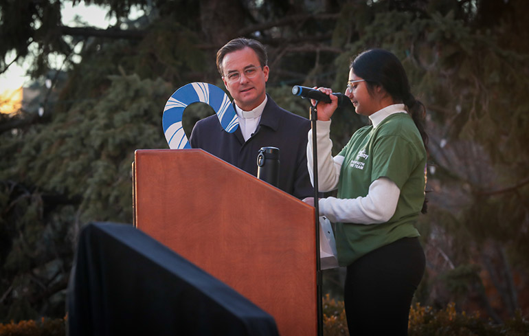 Fr. Hendrickson listens to a student speak at the Celebration of Light ceremony.