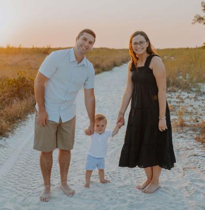 A couple smiles with a child on the beach