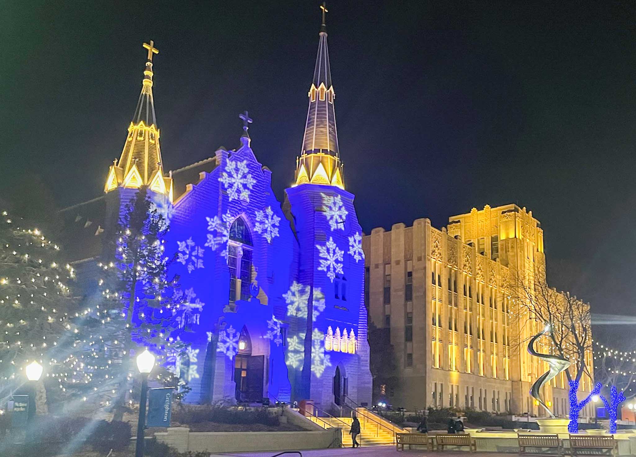 An exterior of a church illuminated with blue lights and white snowflakes