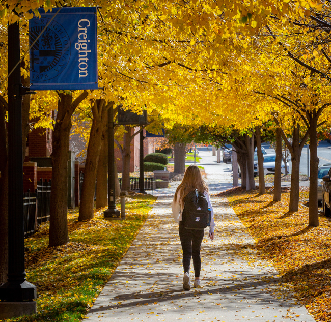 Creighton student walks on campus on a fall day.