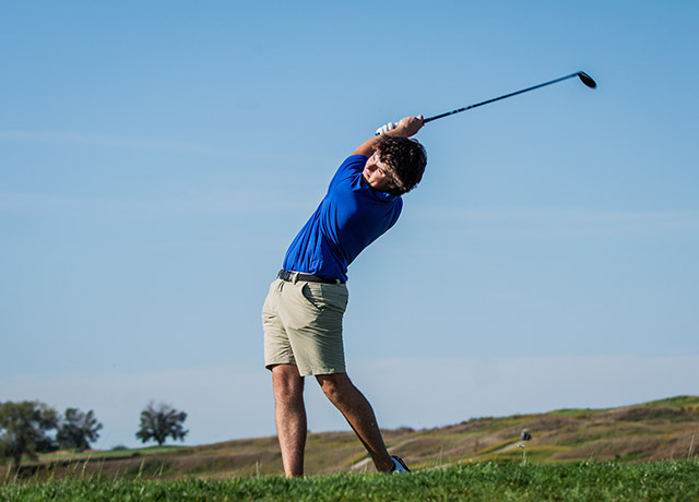 Golfer swinging club on the course