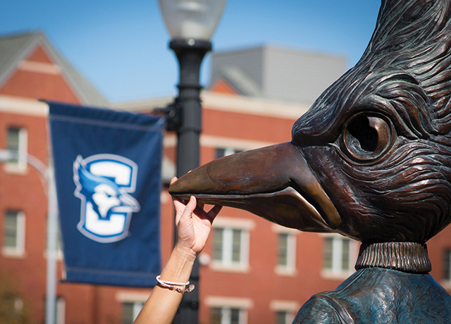 A student touches the beak of the Billy Bluejay statue