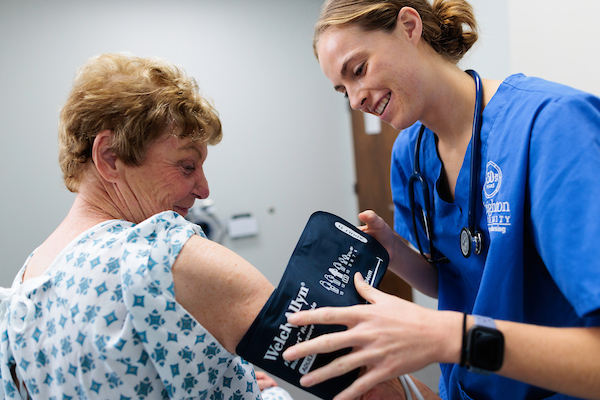 A nursing student helps a patient.