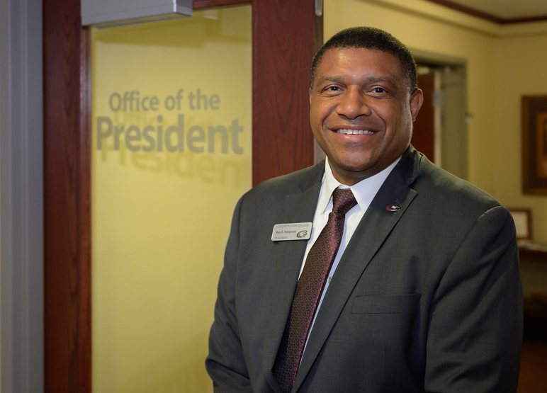 A photo of Ron Patterson smiling outside his office