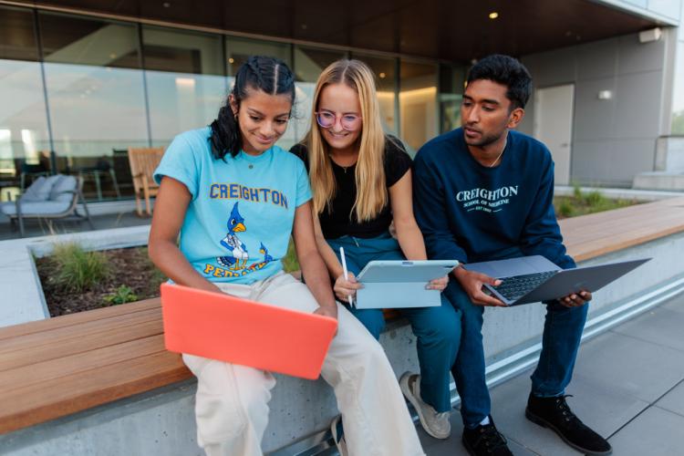 Students sit on a bench and study together