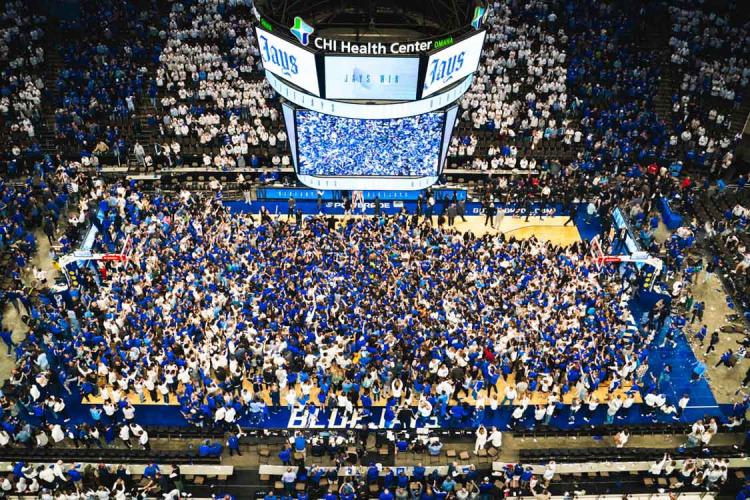 An overhead photo of a basketball court full of fans celebrating a big win