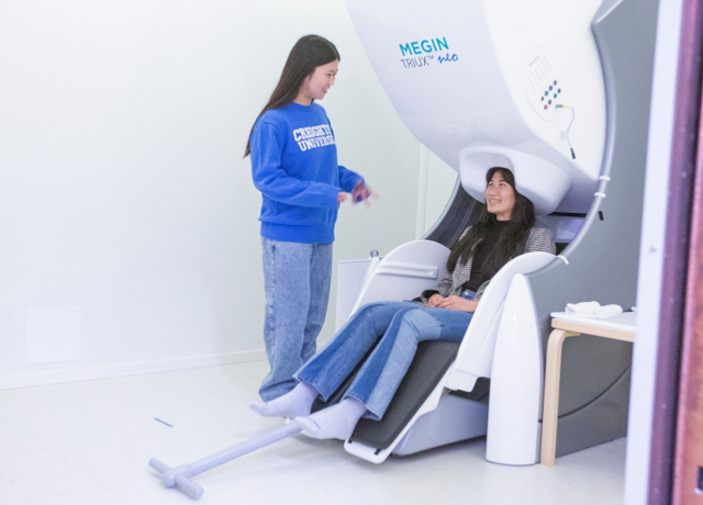 Liana Chinen with a patient at the MEG machine in the PoWER Lab.