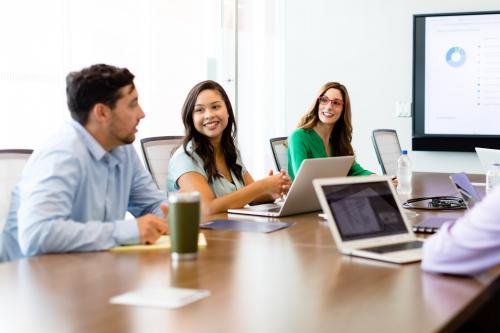 People sit together at a conference room table with their laptops