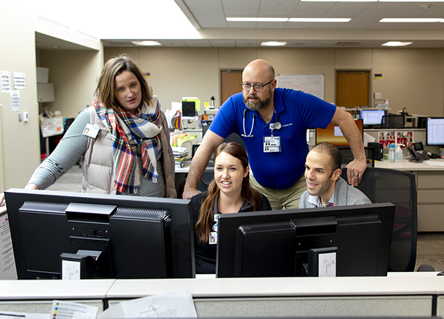 Clinicians work together around a computer.