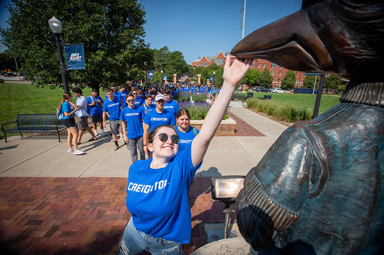 Creighton students tap Billy's beak on the pathway walk.