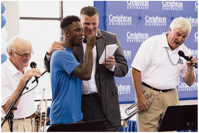 From left: Bill Scott, player Devin Brooks, Coach Greg McDermott and John Scott singing at the dedication of the Championship Center in 2014.