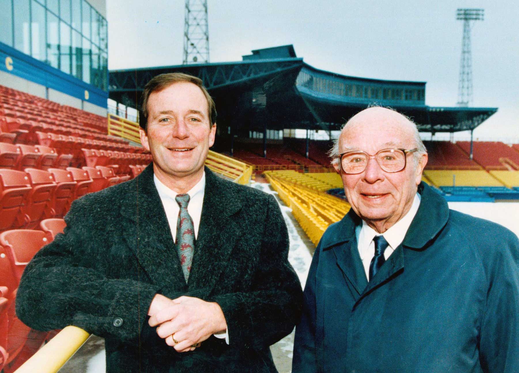 A father and son stand together for a photo inside a baseball stadium
