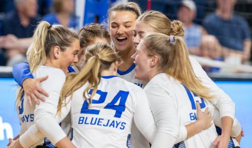 Volleyball players huddle together to celebrate during a match.