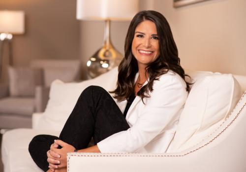 Creighton alumna Lea Pascotto smiles as she sits on a couch