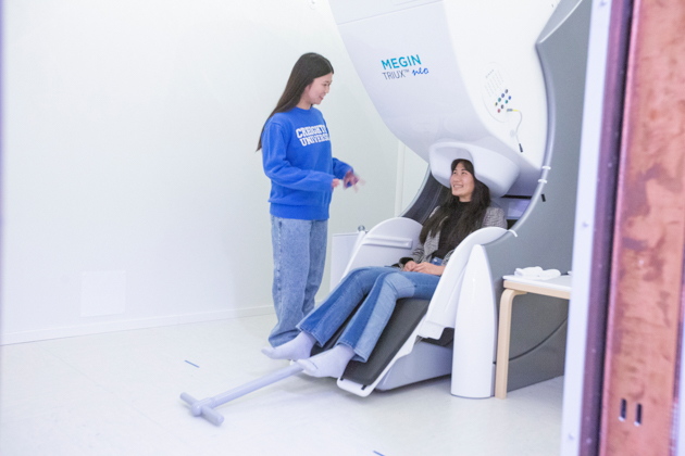 Liana Chinen with a patient at the MEG machine in the PoWER Lab. Liana Chinen with a patient at the MEG machine in the PoWER Lab.