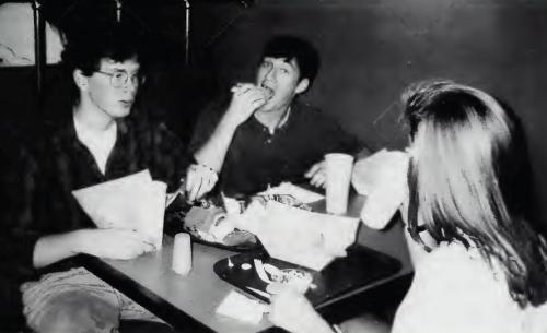 Black and white photo of three students eating at table