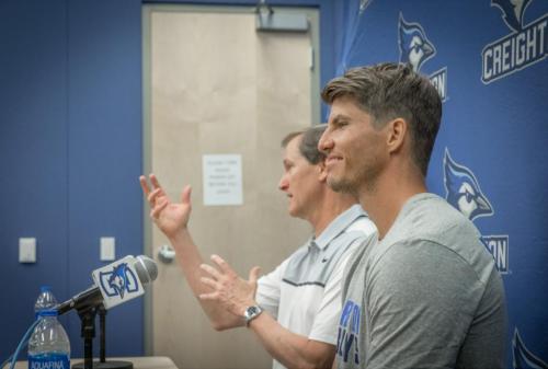 Kyle Korver smiles while Dana Altman speaks at a press conference