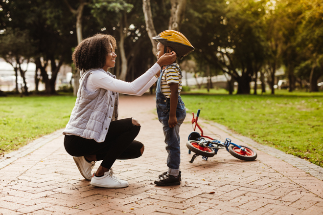 Mother helps child with bike helmet.