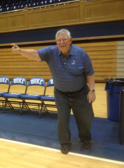 A man points while on the sideline of a basketball court