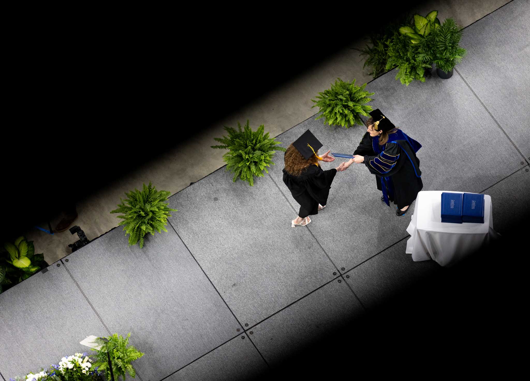 Looking from above an a graduate crossing the stage at commencement