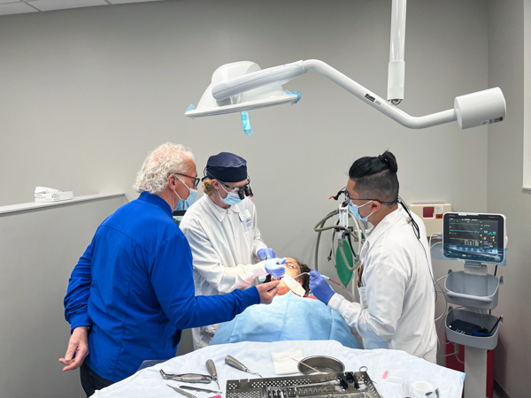 Professor Terry Lanphier and D4 students Dakota Baker and Peter Liang extract a tooth from Michelle Lucius.