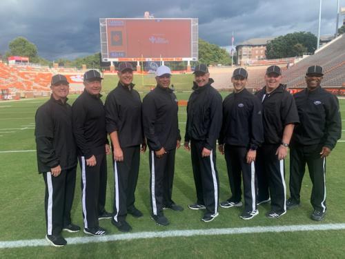 Eight football officials stand together on a field