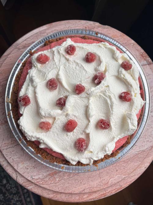 A pie with white frosting and cranberries