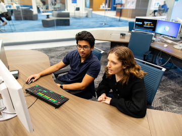 Students look at a computer screen in the HCOB trading room.