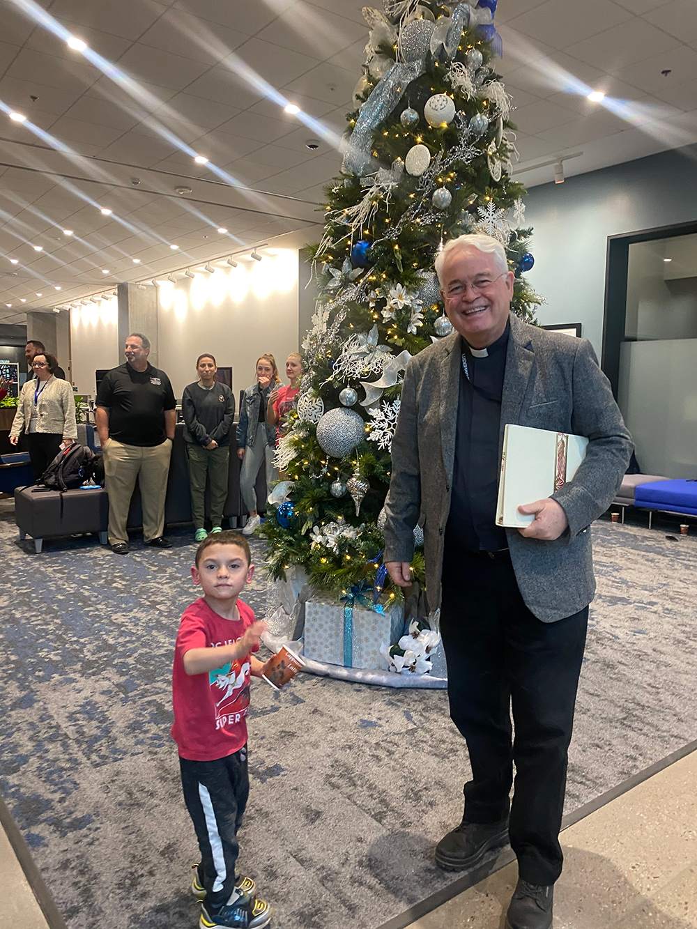 Fr. Kevin and a child after lighting the Christmas tree on the Phoenix campus.