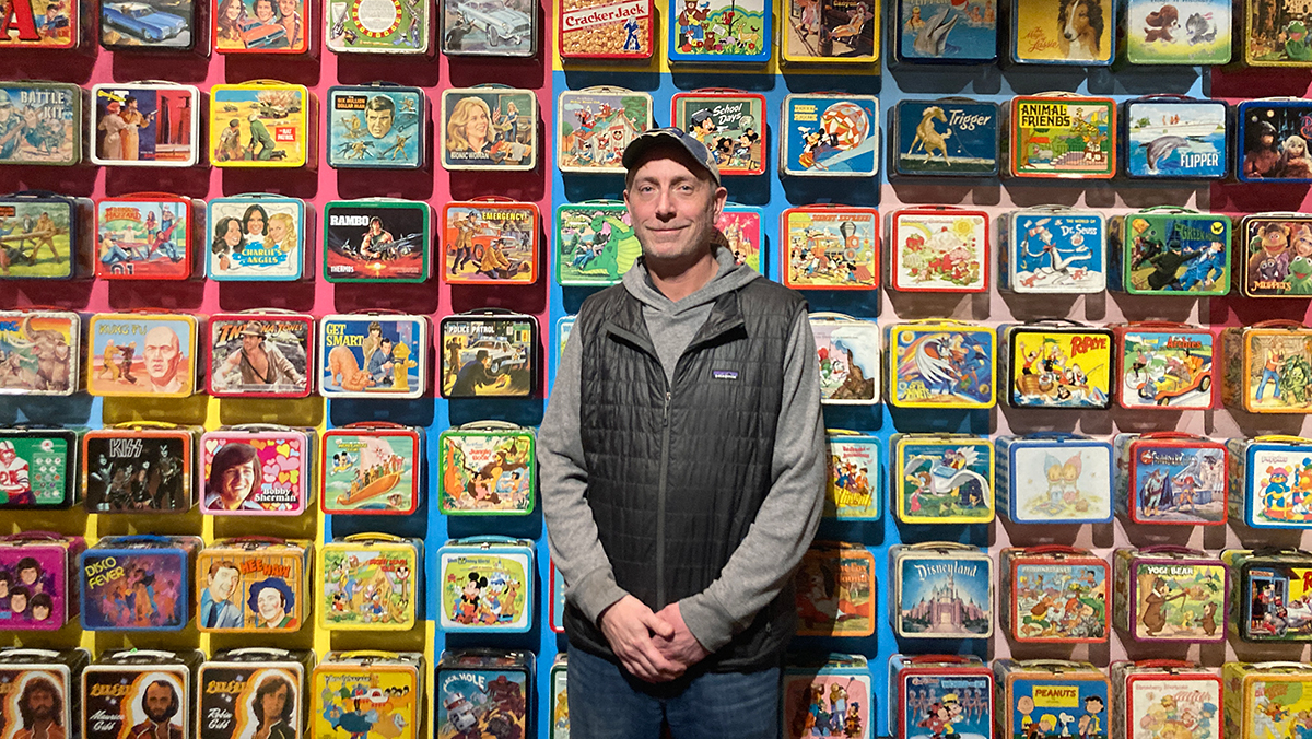 Mark Kelehan pictured in front of a bunch of lunchboxes at his Durham exhibit.