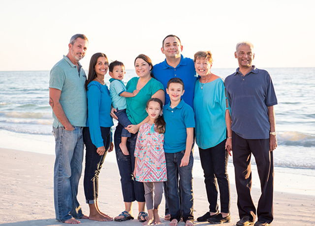 The Mooss family pose for a photo on a beach.