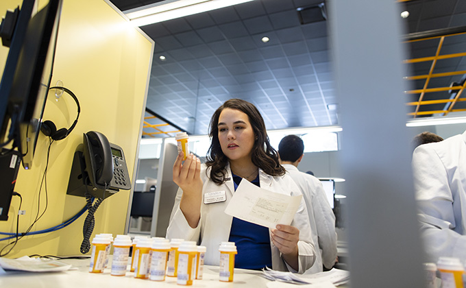 A pharmacy student cross-checks a prescription.