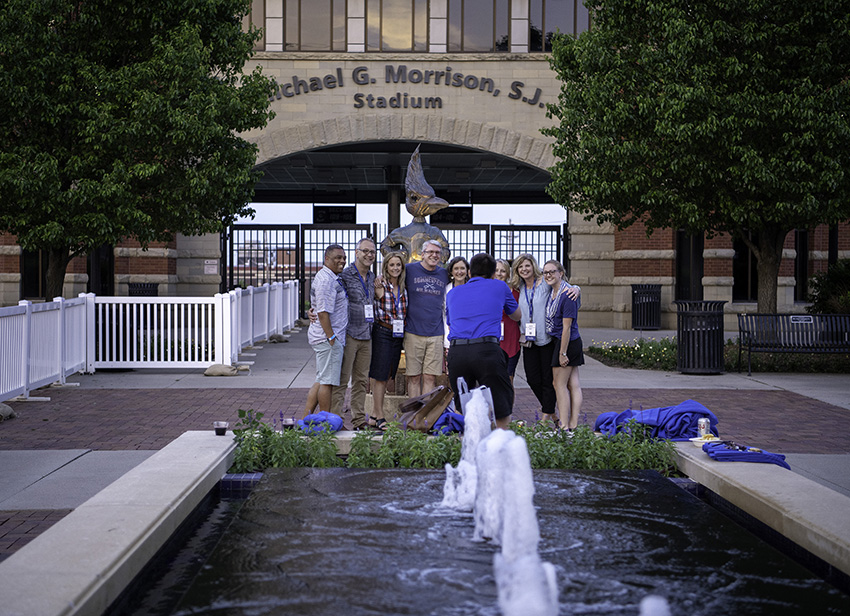 Group of alumni stand in front of Morrison Stadium on Creighton's campus