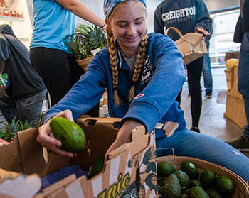 A Creighton student on a service trip packs produce.