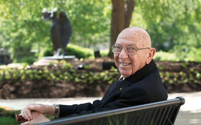 A professor sits on a bench
