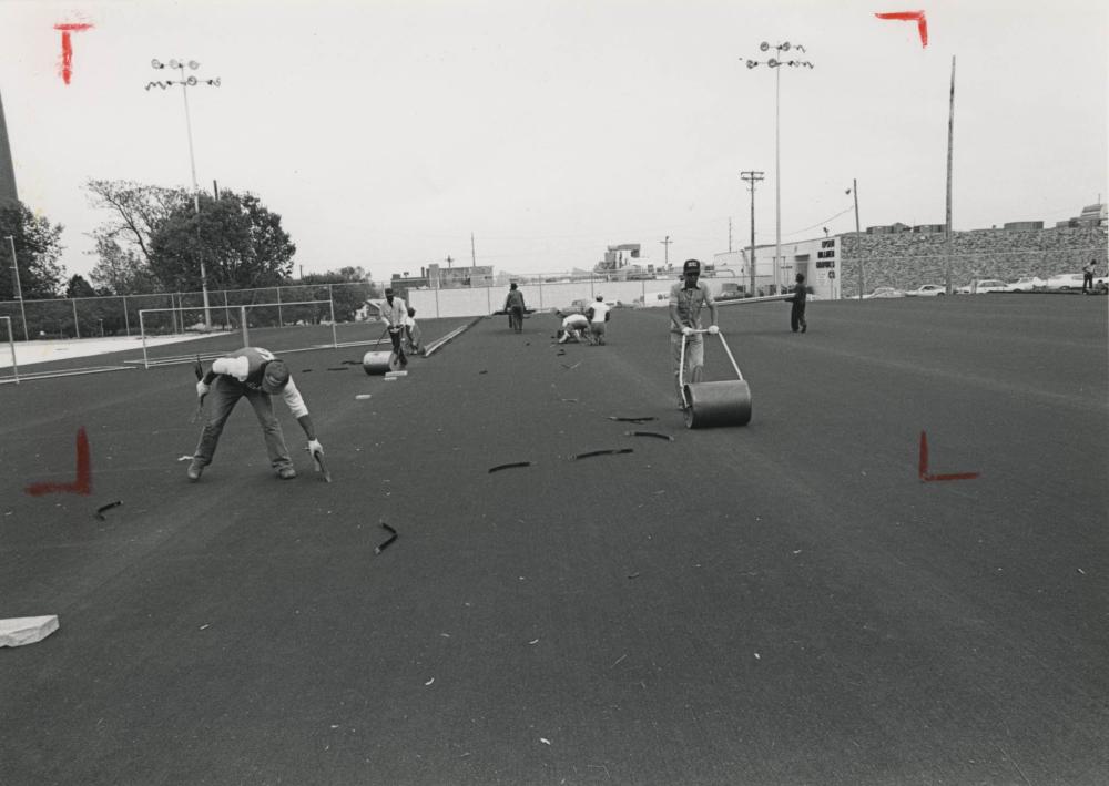 Workers installing turf on the field