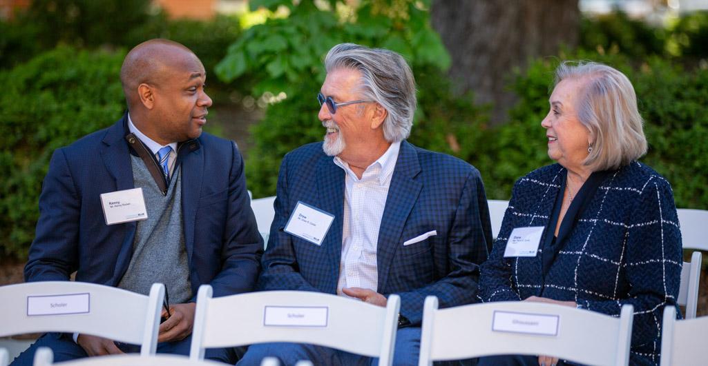 Three people sit and talk before a ribbon cutting ceremony