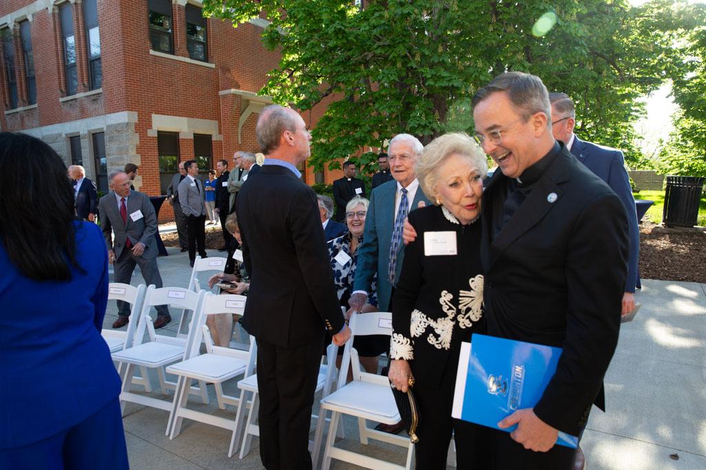 Two people hug as others gather for a ribbon cutting ceremony