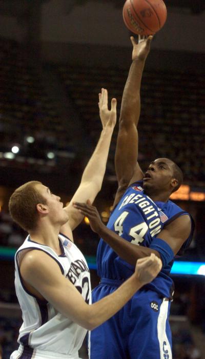A basketball player shoots over a defender