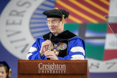 Creighton's president speaks into a microphone