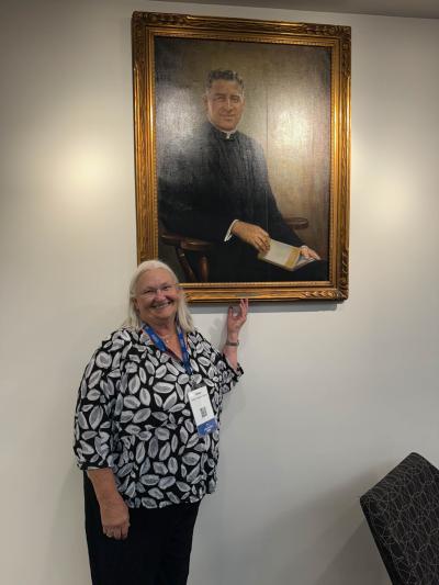 A woman stands next to a framed photograph