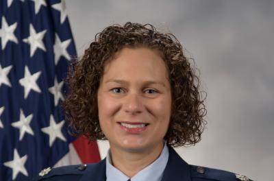Kristen Nichols smiles in a photo with an American flag in the background