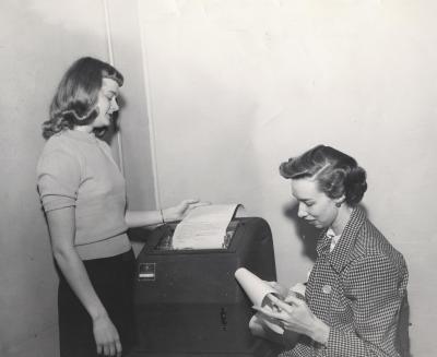 Two students next to a teletype machine