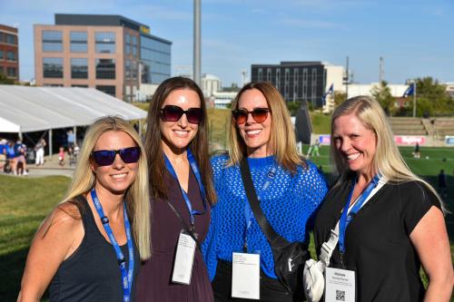 Four women pose for a photograph inside a soccer stadium