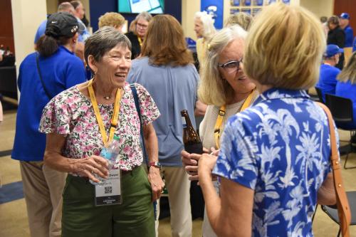 A woman laughs with two former classmates