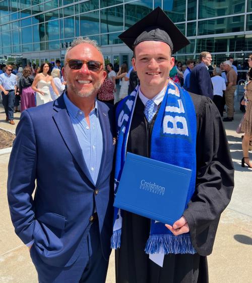 A dad and a son pose for a photo on graduation day